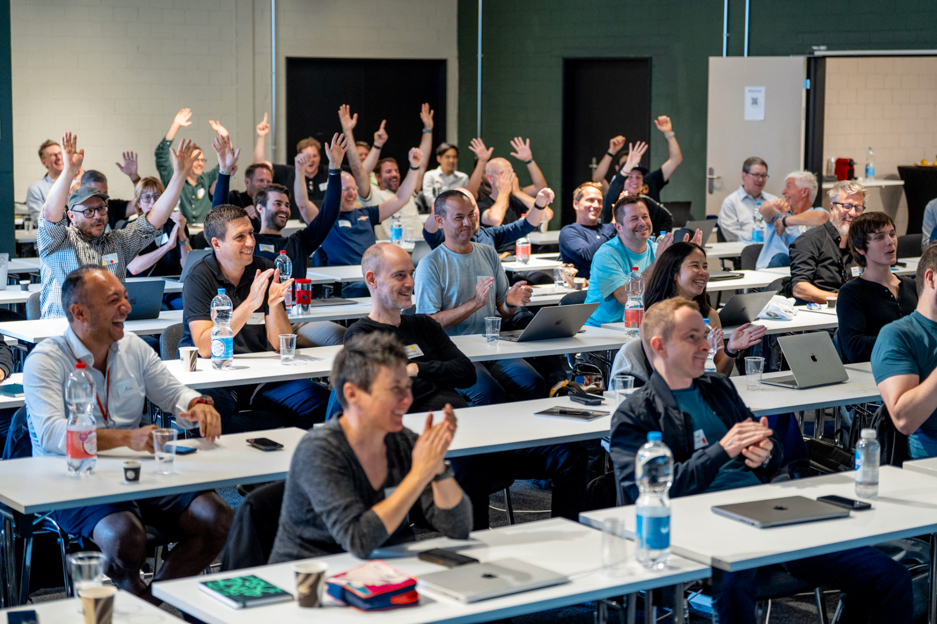 Enthusiastic Vibe Code Fest audience raising their hands during a session