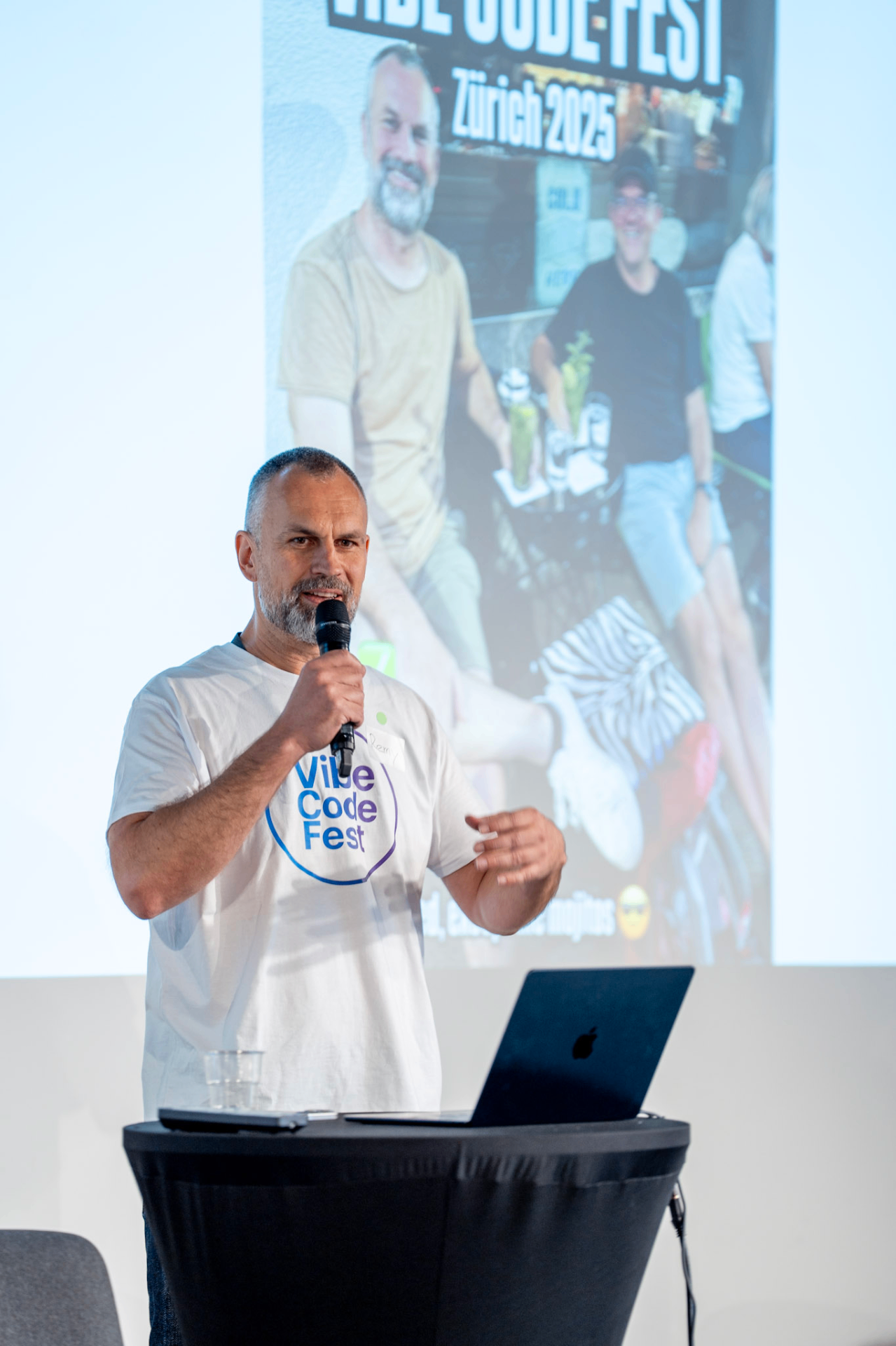 A speaker presenting at Vibe Code Fest in front of a projected screen