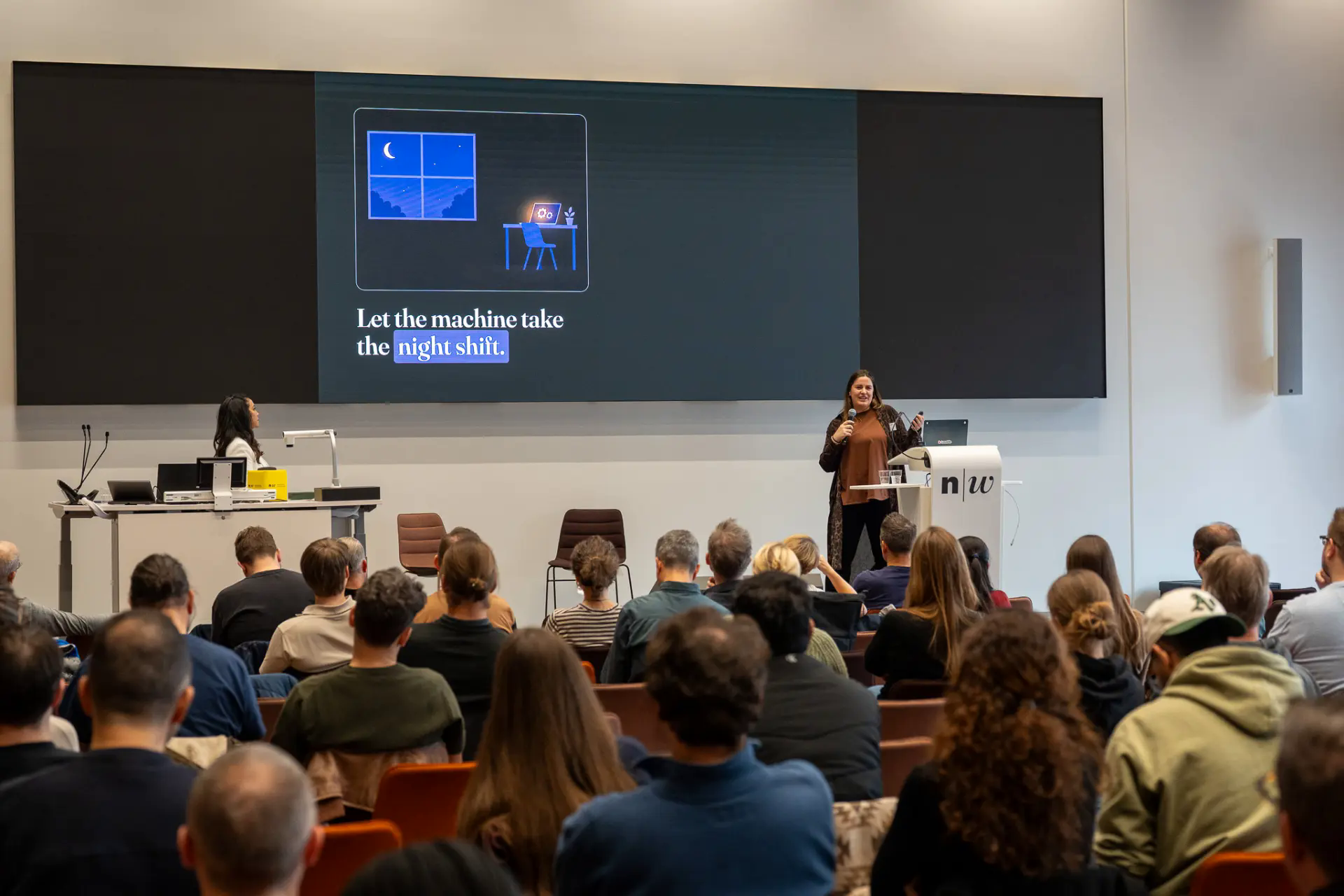 Speaker presenting at the podium in front of a full auditorium