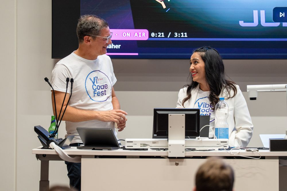 Two presenters sharing a moment at the stage desk